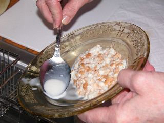 Draining extra milk from the soaked bread